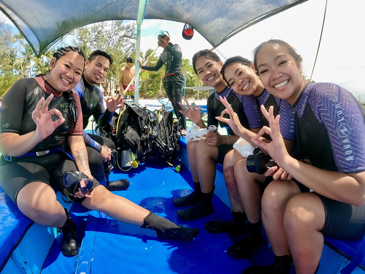 Smiling divers giving the OK sign on the dive boat